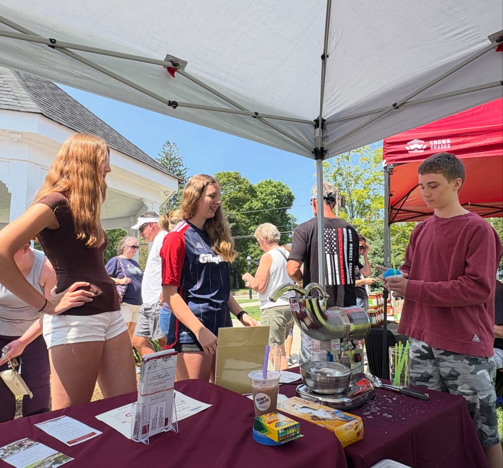 Owen serves snow cones to two farmer's market visitors