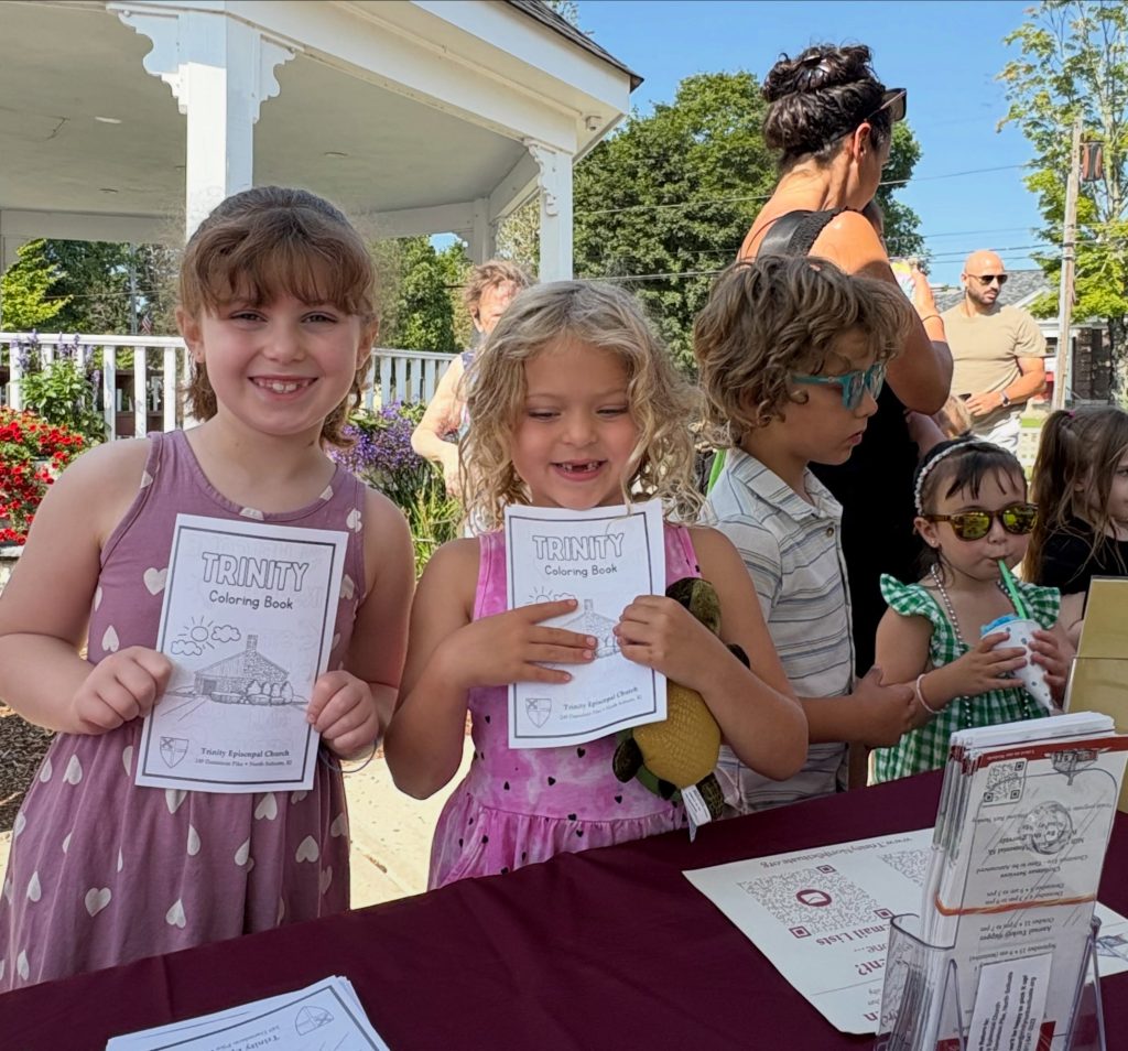 Two young girls at the farmer's market show-off their trinity coloring books.