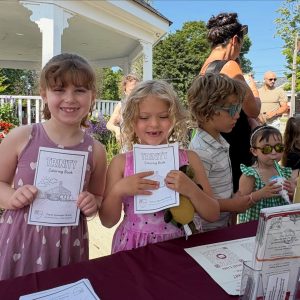 Two young girls at the farmer's market show-off their trinity coloring books.